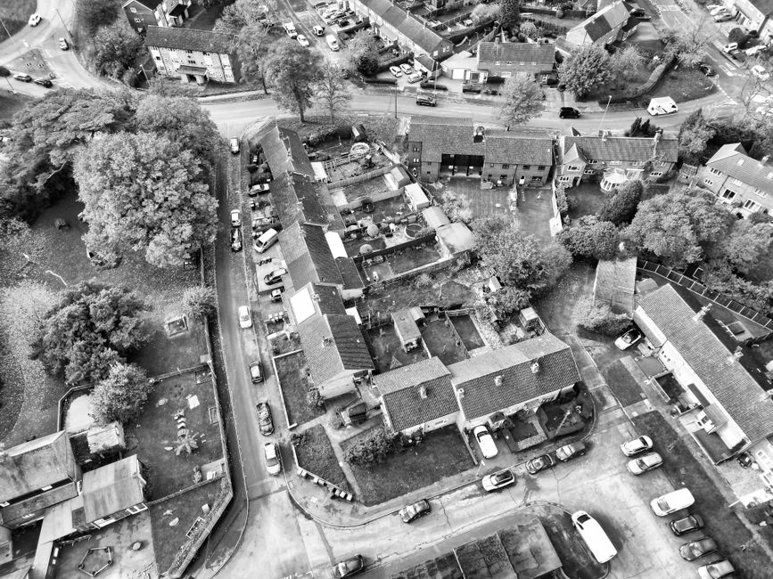 An aerial view of a residential neighbourhood featuring small front gardens and well-maintained hedges. The image shows a variety of houses with different architectural styles, some with bay windows a